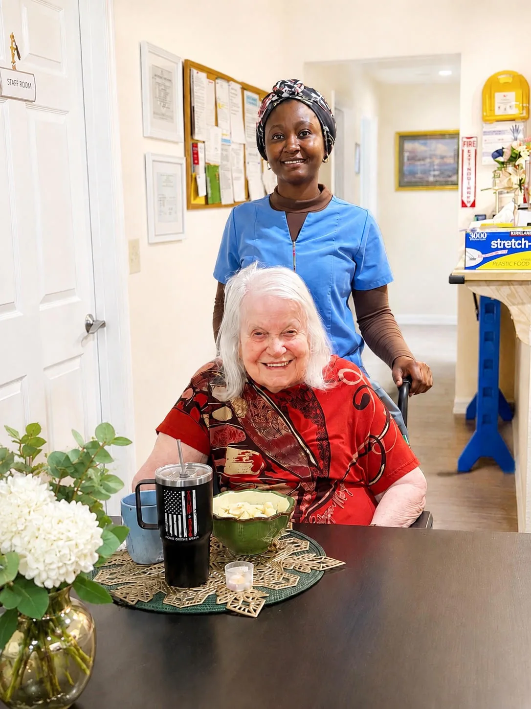 A caregiver standing with a resident at the dining table at A WellCared Adult Family Home