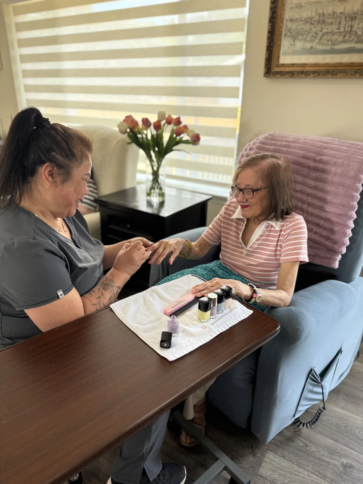 A caregiver painting a resident's nails at the table