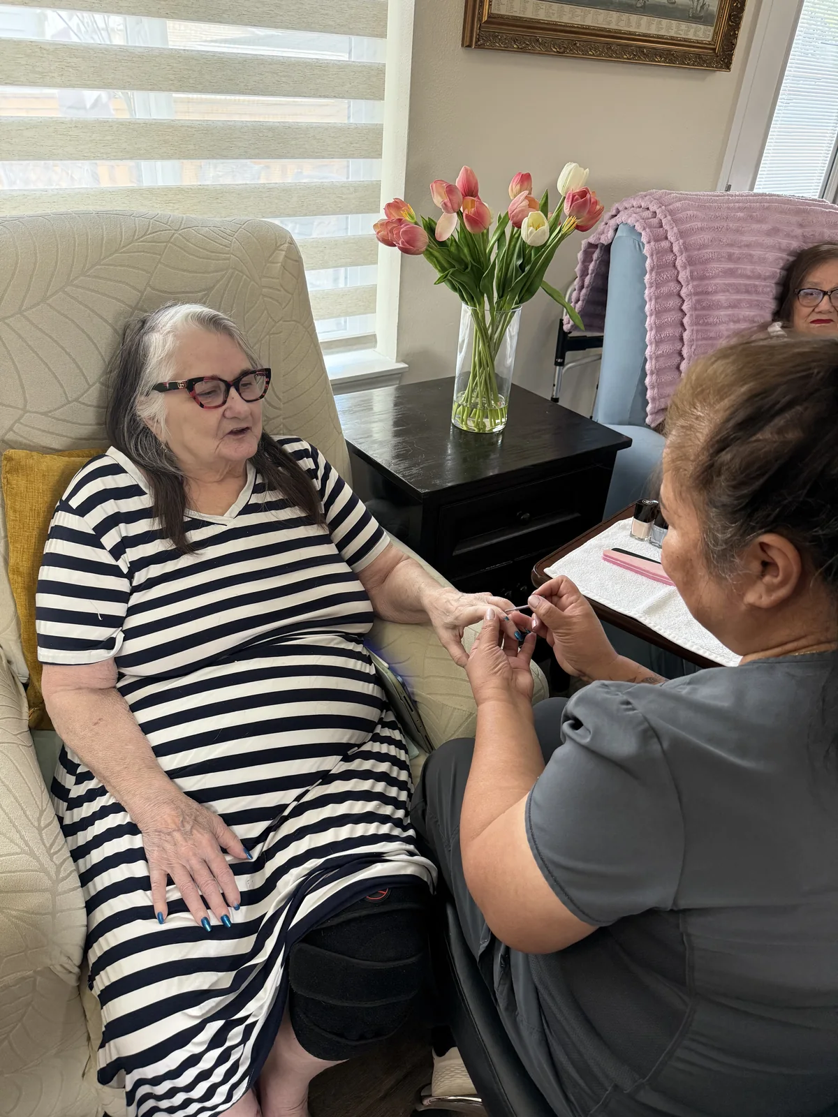 A resident chatting with her caregiver during nail care